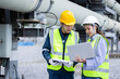 © Sumala - Engineer working at high voltage power substation infrastructure inspection check with safety helmet and vest using laptop and blueprint for maintenance task