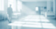 © al-sultan - Blurred figure walks in a bright white hallway with light streaming through windows.