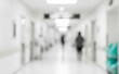 © al-sultan - Blurred hospital hallway with people walking and bright overhead lighting.