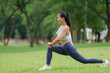 © crizzystudio - Young asian sportswoman stretching legs in a park during summer day