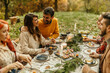 © La Famiglia - Friends enjoying thanksgiving dinner together outdoors in autumn