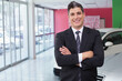 © wavebreak3 - Male sales rep showing white sedan in showroom with floor-to-ceiling glass, red wall, copy space