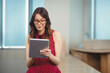 © WavebreakMediaMicro - Woman wearing eyeglasses holding tablet and reading screen in office conference area with blinds