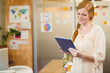 © WavebreakMediaMicro - Red-haired woman reading tablet in modern office meeting area near sticky notes and printed charts