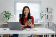 © Phimwilai - Asian businesswoman using smartphone and working with laptop in modern office
