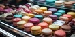 © Lasvu - Assortment of colorful macaroons on cafe showcase with variety of macaron flavours, sweet almond cakes in store, and empty space for text.