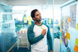 © WavebreakMediaMicro - Asian man standing in office holding yellow marker and studying sticky notes on glass board