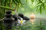 Zen scene with bamboo spout, black stones, plumeria flower, and lit candle in tranquil pond