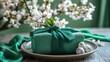 © Lasvu - Wrapping Easter gift - green fabric, card, napkin on plate, close-up.