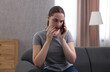 © New Africa - Depressed woman calling hotline for mental health help on sofa at home