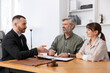 © New Africa - Couple having meeting with professional lawyer at wooden desk indoors