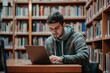 © Pavel - Young male student engages in focused study while using a laptop in a school library filled with books