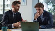 © stockbusters - Business partners discussing project at laptop sitting corporate office closeup