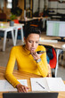 © Wavebreak Media - Senior woman in yellow sweater speaking into smartphone at office desk with laptop and spreadsheets