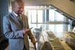© Wavebreak Media - African American man in suit pulling suitcase and checking smartphone at airport gate, copy space