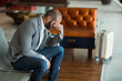 © Wavebreak Media - Man is sitting hunched forward on perforated metal bench in airport lounge beside rolling suitcase