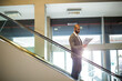 © Wavebreak Media - Male business professional standing on escalator railing holding papers in office lobby, copy space