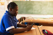 © Wavebreak Media - School student sitting at wooden desk using smartphone in classroom, with stationery on desk