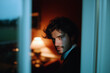 © Amy - Stylish young man in suit looking down in moody indoor lighting, thoughtful expression near window