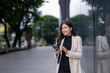 © Wasana - A woman is standing on a sidewalk holding a tablet and smiling