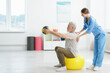© New Africa - Doctor and patient exercising with medicine ball in clinic, space for text