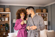 © Dorde - Smiling Couple in Bathrobes Sharing Morning Coffee in a Bright and Cozy Living Room Setting