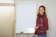 © Wavebreak Media - female presenter in red blouse standing beside flip chart in boardroom holding marker, copy space