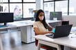 © Wavebreak Media - Woman wearing pale pink face mask typing on laptop at open-plan desk with notebook