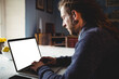 © Wavebreak Media - bearded man typing on laptop near bright window, with citrus bowl and smartphone on patterned cloth