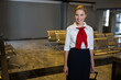 © Wavebreak Media - Female flight attendant standing near seats at airport lounge with rolling suitcase, copy space