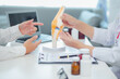 © ThawKyar - A physical therapist examines a patient's knee injury using a model to demonstrate the patient's knee joint and ligaments to detect pain. Specialized orthopedic medical concept.