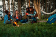 © DusanJelicic - Friends creating cozy camping atmosphere in woodland setting. Authentic moment capturing diverse group sharing stories and drinks at golden hour.