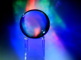 Wall Mural - a clear glass ball is sitting on a pedestal. colorful background. abstract graphic background. light