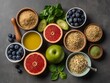 © ANJITSYA - A flat lay of various healthy superfoods including blueberries, grapefruit, green apple, avocado, olive oil, spinach, seeds, and grains, arranged neatly on a dark textured surface.