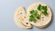 © mahmud - Stack of tortillas with fresh parsley on a gray background