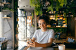 © Dusan Petkovic - Portrait of happy multicultural girl sitting in cafe with cellphone in hands and smiling at camera.