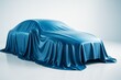 © Pixels Hunter - Covered car silhouette under shiny blue cloth on glossy floor with soft light background, symbolizing future transport concept unveiling.