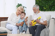 © New Africa - Grandparents teaching their grandson to play guitar on sofa at home