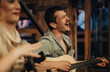 © qunica.com - A joyful musician playing guitar and singing passionately, embodying live music and heartfelt emotion in a cozy atmosphere.