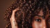 Close-up of voluminous curly hair and confident gaze in beauty advertising hairdresser style.
