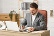 © Pixel-Shot - Businessman working with calculator at table in office