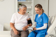 © Pixel-Shot - Senior woman with nurse measuring blood pressure in clinic