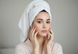 © Rehena - Woman with towel on head touching her face after shower, skincare routine ai generated