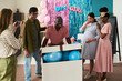 © pressmaster - Black man emerging from large box filled with blue balloons while pregnant woman and friends reacting with excitement
