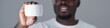 © pressmaster - Close-up of Black person holding white container with fingers visible, focusing on product. Blurred background adding depth