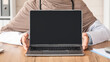 © Prostock-studio - Unrecognizable female doctor muslim woman in hijab showing laptop with blank screen, mockup, copy space. Cropped of doctor using modern technologies in job, working, training online, clinic interior