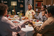 © Seventyfour - Cropped shot of Black family members holding hands sitting around table praying before festive dinner in dining room