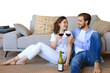 © ty - Happy couple sitting, relaxing on floor, drinking red wine. Smiling young husband and wife rest enjoy romantic date on family weekend together on a transparent background