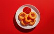 © Denis Renkas - Top-down view of crispy onion rings plate with ketchup on red surface.