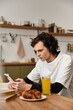 © LIGHTFIELD STUDIOS - Young man enjoys a cozy morning at home with snacks and music while relaxing with his phone